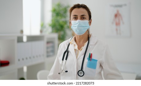 Middle Age Hispanic Woman Wearing Doctor Uniform And Medical Mask At Clinic