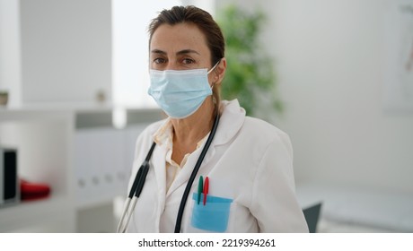 Middle Age Hispanic Woman Wearing Doctor Uniform And Medical Mask At Clinic