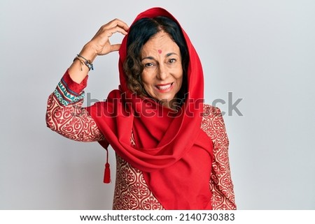 Middle age hispanic woman wearing tradition sherwani saree clothes confuse and wonder about question. uncertain with doubt, thinking with hand on head. pensive concept. 