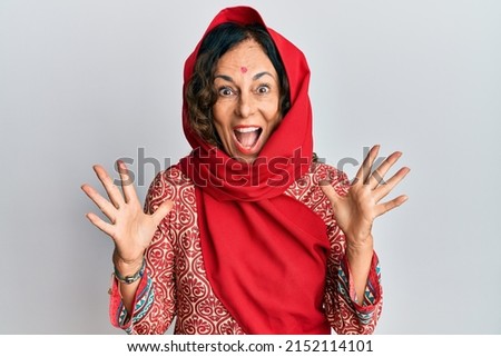 Middle age hispanic woman wearing tradition sherwani saree clothes celebrating crazy and amazed for success with arms raised and open eyes screaming excited. winner concept 