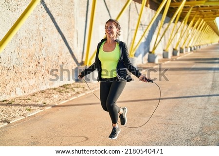 Middle age hispanic woman working out jumping rope at promenade