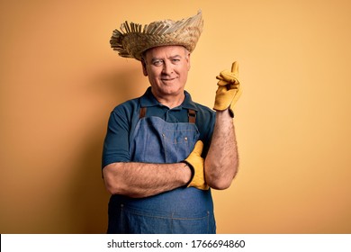 Middle Age Hoary Farmer Man Wearing Apron And Hat Over Isolated Yellow Background With A Big Smile On Face, Pointing With Hand And Finger To The Side Looking At The Camera.