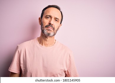 Middle age hoary man wearing casual t-shirt standing over isolated pink background Relaxed with serious expression on face. Simple and natural looking at the camera. - Powered by Shutterstock