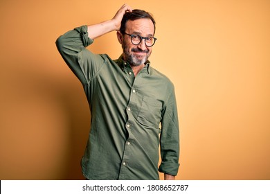 Middle age hoary man wearing casual green shirt and glasses over isolated yellow background confuse and wonder about question. Uncertain with doubt, thinking with hand on head. Pensive concept. - Shutterstock ID 1808652787