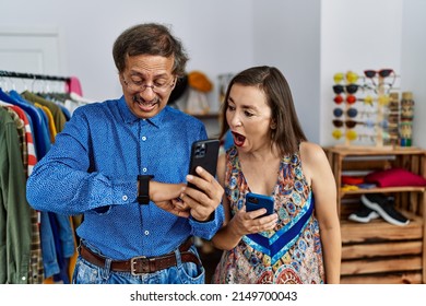 Middle Age Interracial Couple At Retail Shop Using Smartphone Looking At The Watch Time Worried, Afraid Of Getting Late 