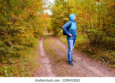 A Middle Age Male Hiker With A Hoodie And Backpack.Man Standing Along The Autumn Forest Path Way.A Healthy Lifestyle In Nature.