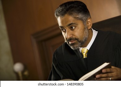 Middle Age Male Judge With Book Looking Away In Court Room