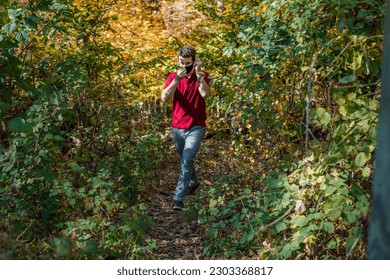 Middle age man adjusting face mask walking in woods - Powered by Shutterstock