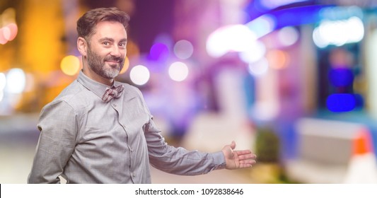 Middle Age Man, With Beard And Bow Tie Confident And Happy With A Big Natural Smile Inviting To Enter At Night Club