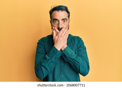 Middle age man with beard and grey hair wearing business clothes shocked covering mouth with hands for mistake. secret concept.  - Powered by Shutterstock