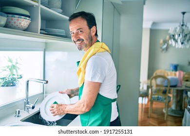 Middle age man with beard smiling happy washing dishes at home - Powered by Shutterstock