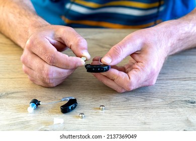 A Middle Age Man Changing Battery The Hearing Aid Hearing Amplifier Before Wear.