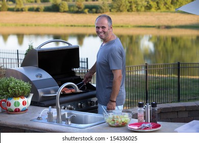 Middle age man cooking salmons at the outside kitchen barbecue
