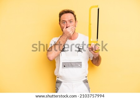 middle age man covering mouth with hands with a shocked. handyman and repair concept