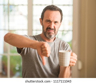 Middle Age Man Drinking Coffee In A Cup With Angry Face, Negative Sign Showing Dislike With Thumbs Down, Rejection Concept