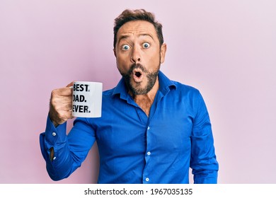 Middle Age Man Drinking Mug Of Coffee With Best Dad Ever Message Scared And Amazed With Open Mouth For Surprise, Disbelief Face 