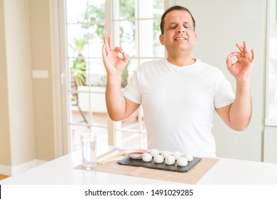 Middle Age Man Eating Asian Dumplings At Home Relax And Smiling With Eyes Closed Doing Meditation Gesture With Fingers. Yoga Concept.