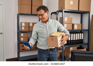 Middle Age Man Ecommerce Business Worker Using Smartphone And Holding Package At Office