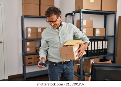 Middle Age Man Ecommerce Business Worker Using Smartphone And Holding Package At Office