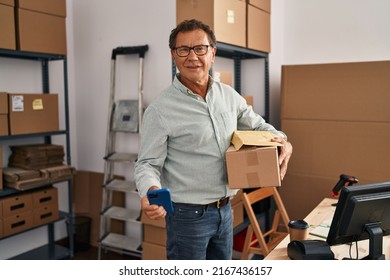 Middle Age Man Ecommerce Business Worker Using Smartphone And Holding Package At Office