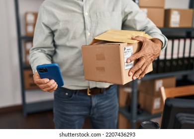 Middle Age Man Ecommerce Business Worker Using Smartphone And Holding Package At Office