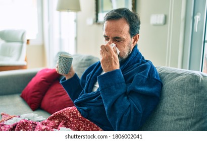 Middle Age Man Feeling Sick With Cold And Fever At Home, Ill With Flu Disease Sitting On The Sofa