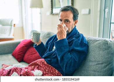 Middle Age Man Feeling Sick With Cold And Fever At Home, Ill With Flu Disease Sitting On The Sofa