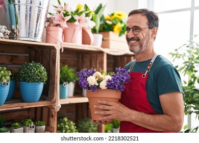 Middle age man florist holding plant of shelving at florist - Powered by Shutterstock