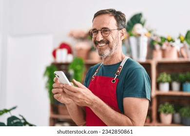 Middle age man florist smiling confident using smartphone at florist - Powered by Shutterstock