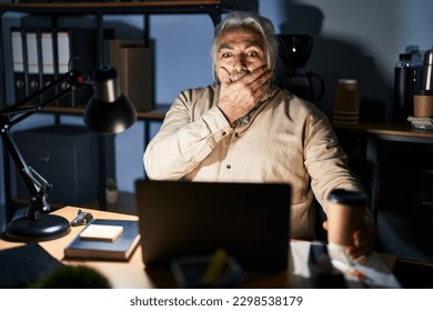 Middle age man with grey hair working at the office at night shocked covering mouth with hands for mistake. secret concept.  - Powered by Shutterstock