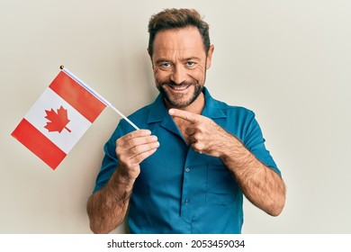 Middle Age Man Holding Canada Flag Smiling Happy Pointing With Hand And Finger 