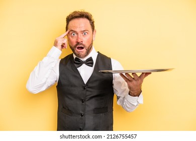 Middle Age Man Looking Surprised, Realizing A New Thought, Idea Or Concept. Waiter Concept With Tray