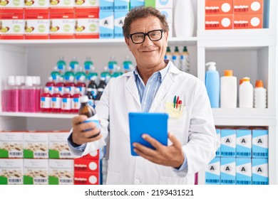 Middle Age Man Pharmacist Using Touchpad Holding Medicine Bottle At Pharmacy