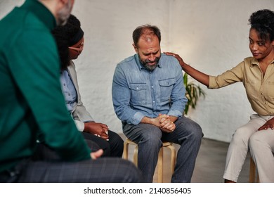 Middle age man sharing struggles during support group meeting with multiracial people siting in circle and comforting him - Powered by Shutterstock