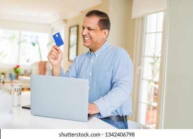 Middle age man showing credit card while using laptop Stock Photo