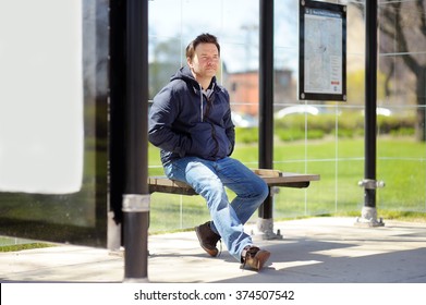 Middle age man sitting on bench on bus stop 
