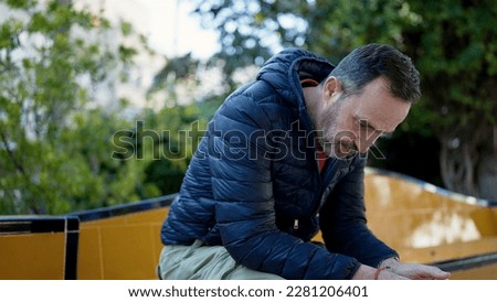 Middle age man sitting on bench with worried expression at park