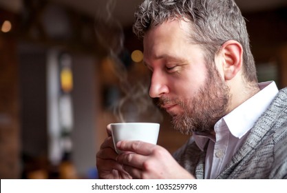 Middle Age Man Smelling Aroma Of Coffee In The Cafe