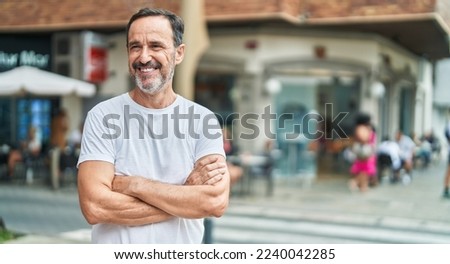 Middle age man standing with arms crossed gesture at street