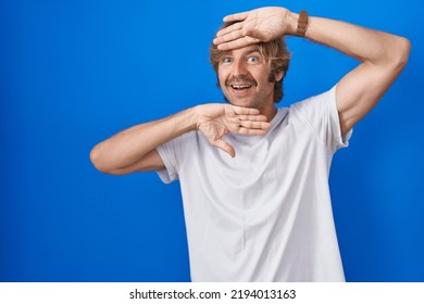 Middle Age Man Standing Over Blue Background Smiling Cheerful Playing Peek A Boo With Hands Showing Face. Surprised And Exited 