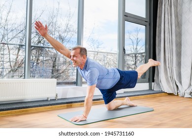 Middle Age Man Stay On Floor Mat In Plank Pose, Stretch Hands And Legs At Light Studio Background, Healthy Workout. Plank With Opposite Arm And Leg Lift.