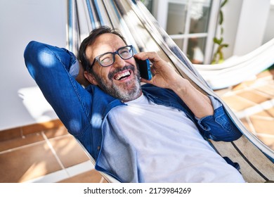 Middle age man talking on the smartphone lying on hammock at terrace home - Powered by Shutterstock