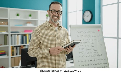 Middle age man teacher teaching lesson holding book at classroom - Powered by Shutterstock