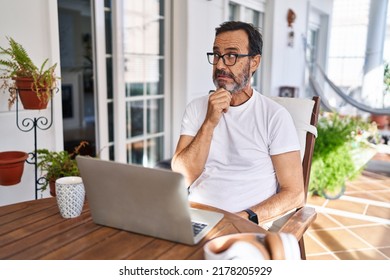 Middle Age Man Using Computer Laptop At Home Thinking Worried About A Question, Concerned And Nervous With Hand On Chin 