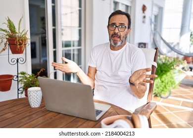 Middle Age Man Using Computer Laptop At Home Clueless And Confused With Open Arms, No Idea Concept. 