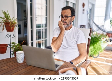 Middle Age Man Using Computer Laptop At Home Looking Stressed And Nervous With Hands On Mouth Biting Nails. Anxiety Problem. 