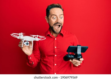Middle age man using drone celebrating crazy and amazed for success with open eyes screaming excited. 