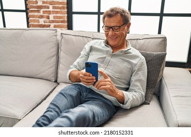 Middle age man using smartphone sitting on sofa at home - Powered by Shutterstock