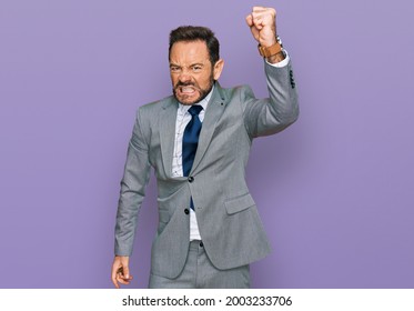 Middle age man wearing business clothes angry and mad raising fist frustrated and furious while shouting with anger. rage and aggressive concept.  - Shutterstock ID 2003233706
