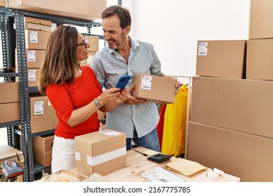 Middle Age Man And Woman Business Partners Using Smartphone Holding Package At Storehouse